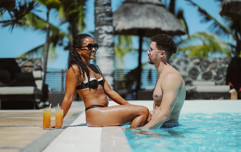 Un couple profite de la piscine au soleil avec des cocktails